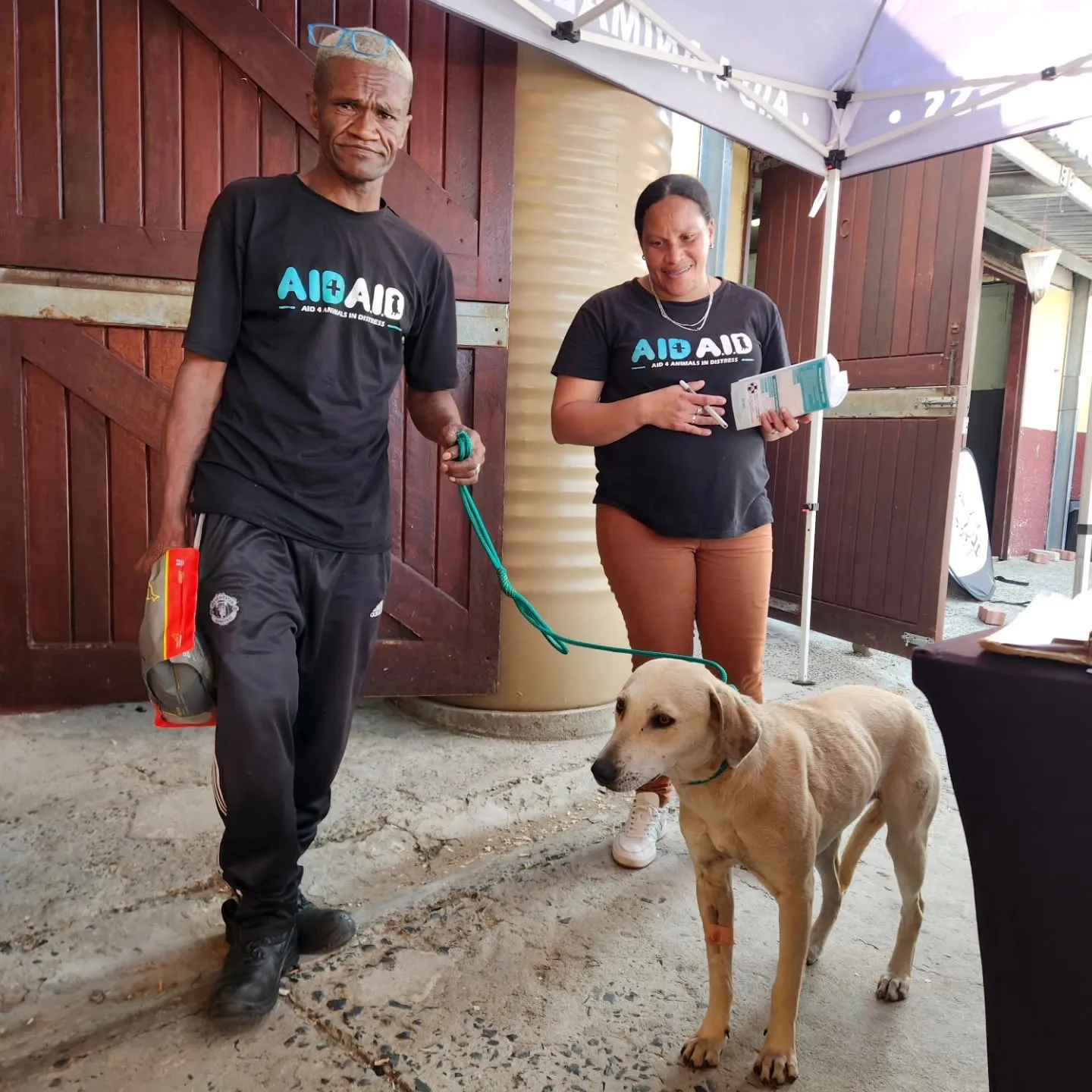 Aid4Aid field workers in branded shirts at a sterilisation day, in front of the Aid4Aid and SPCA banners.