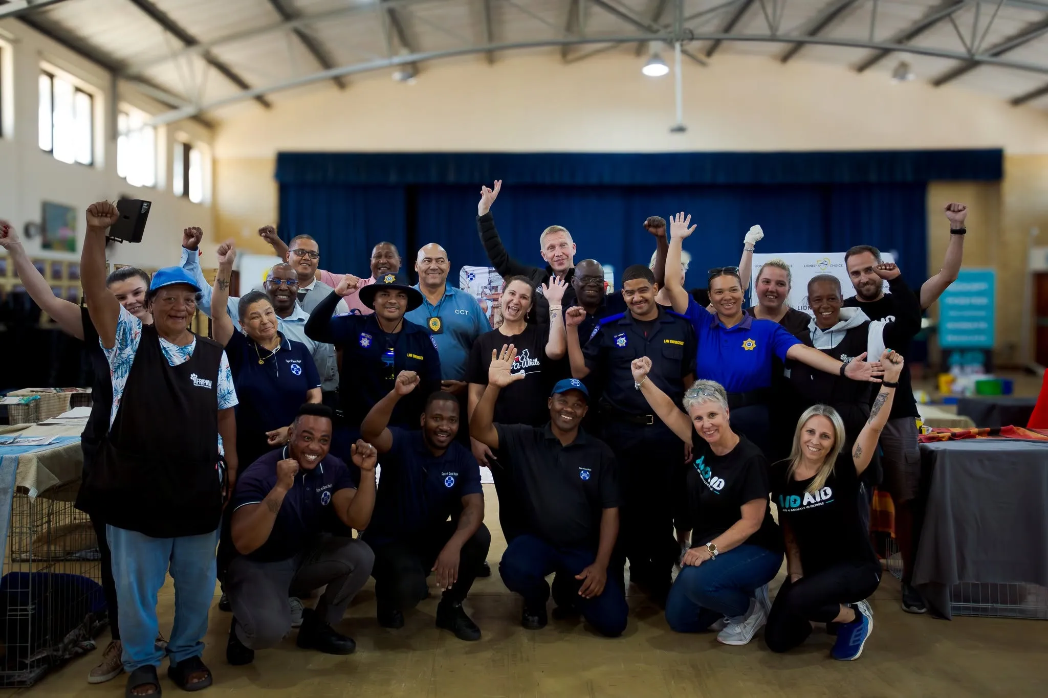 Volunteers, SPCA staff and City law-enforcement officers packed together in the hall with their arms raised, cheering at the camera.